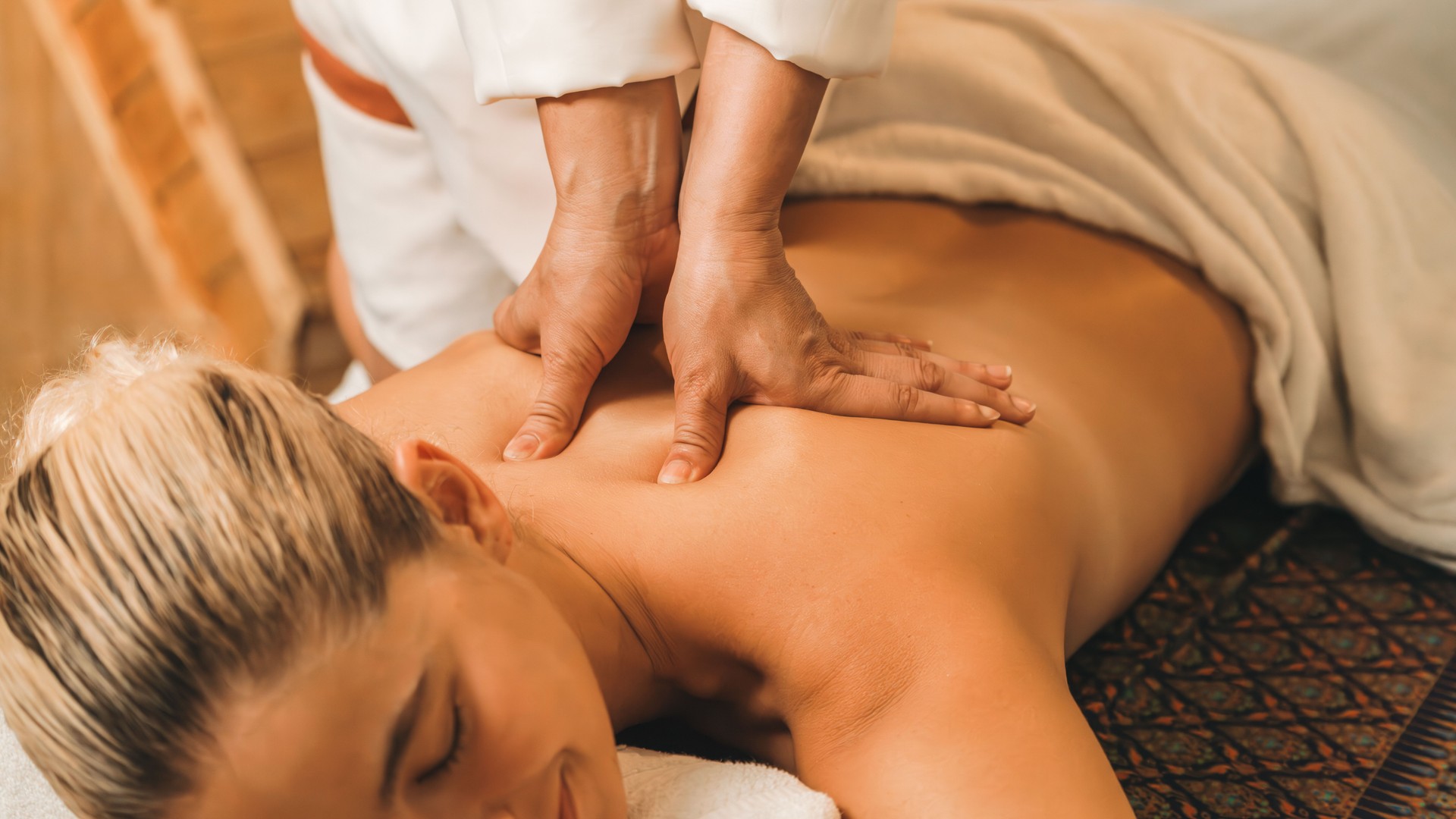 Attractive caucasian woman having back massage at warm sauna room. Tranquility.