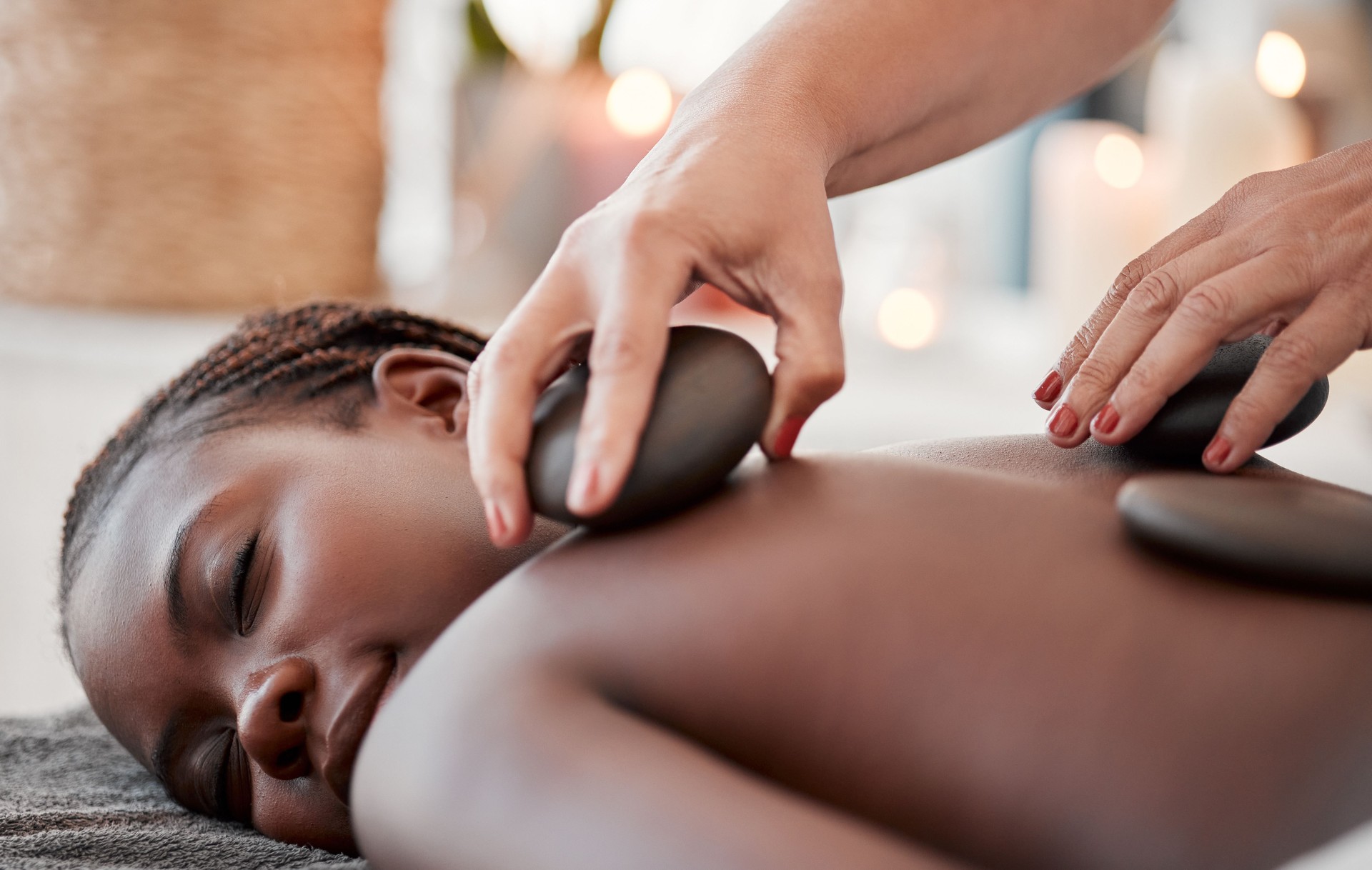 Black woman, hot stone massage, spa and hands of masseuse, holistic and wellness, therapy and treatment. Health, peace of mind and rocks with zen, stress relief for people and back skin detox